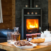 Challet Foehn's living room warm and inviting with its wood burner & afternoon tea laid out to tuck into after skiing.